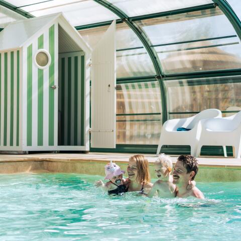 Una familia disfruta de una piscina cubierta climatizada durante sus vacaciones de camping