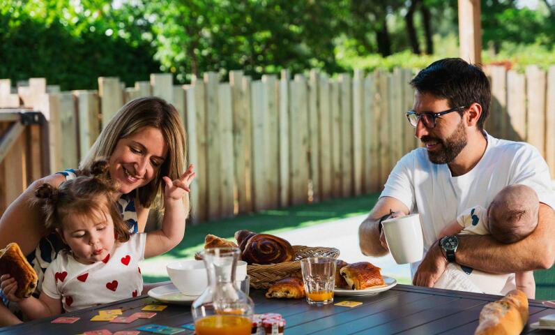Une famille à l'ombre de la terrasse d'un mobil-home