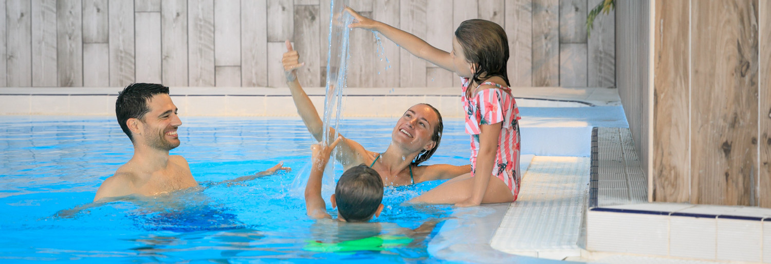 Famille profitant d’une piscine couverte chauffée pendant les vacances au camping