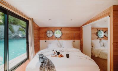 Chambre en bois avec lit double et vue sur une rivière turquoise depuis l'hébergement