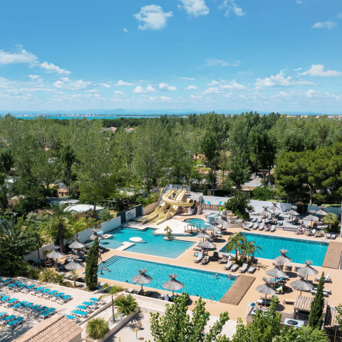 Piscine extérieure du camping Les Jardins de Tivoli avec transats et parasols