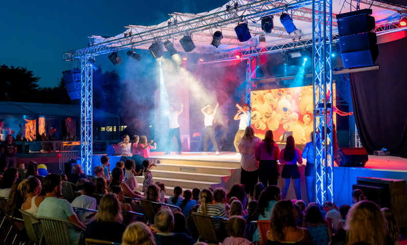 Vacanciers assistant à une animation musicale sur la scène d’un camping Sunêlia lors d’une soirée