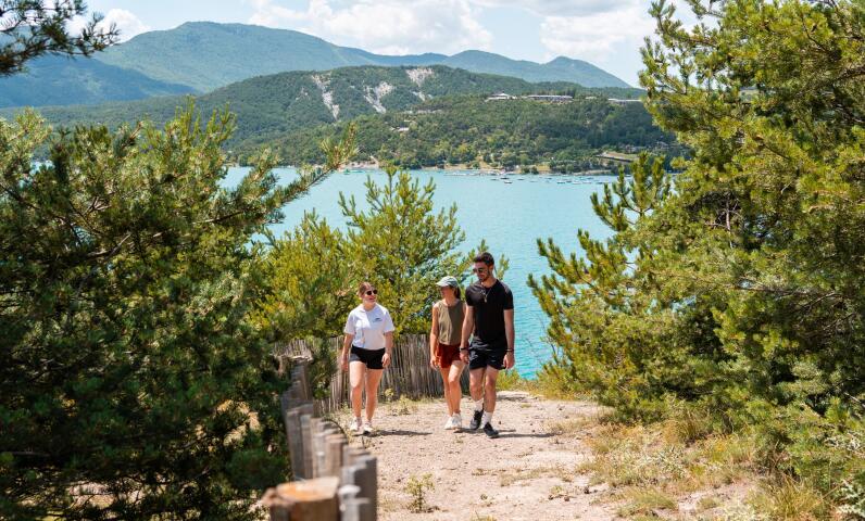 Escursionisti su un sentiero di montagna in estate, con un lago sullo sfondo