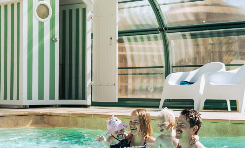 Familie geniet van verwarmd binnenzwembad tijdens kampeervakantie