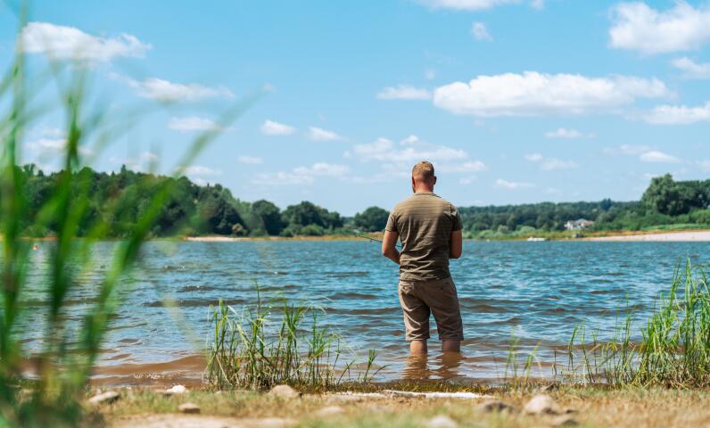 Iemand aan de oever van een bergmeer in de zomer